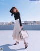 A woman standing on top of a roof holding a white bag.