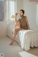 A woman sitting on a bed drinking from a glass.