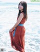 A woman in a red dress standing in the ocean.