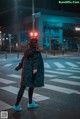 A woman walking across a crosswalk at night.