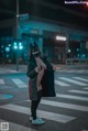 A woman wearing a cat mask standing in the middle of a street.