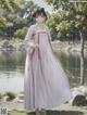 A woman in a white dress standing in front of a lake.