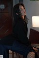 A woman sitting on a chair next to a lamp.