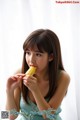 A young woman eating a piece of corn on the cob.