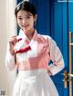 A woman in a pink and white hanbok poses for a picture.