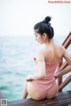 A woman in a pink bathing suit sitting on a wooden bench.