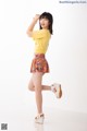 A woman in a yellow shirt and a colorful skirt.