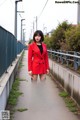 A woman in a red blazer and black tights standing on a sidewalk.