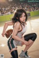 A woman in a basketball uniform crouching on a basketball court.