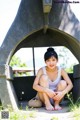 A woman sitting on the ground in front of a stone structure.