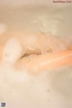 A close up of a person's hand in a bathtub filled with foam.