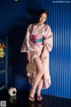 A woman in a pink kimono posing for a picture.