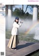 A woman standing in front of a fountain with a rainbow.