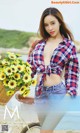 A woman standing next to a bike holding a basket of sunflowers.