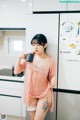 A woman in a pink robe holding a cup of coffee.