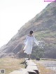 A woman in a white dress is walking on a path.