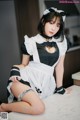 A woman in a maid outfit sitting on a kitchen counter.