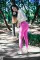 A woman in pink leggings and a white sweatshirt is posing for a picture.