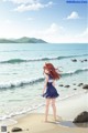 A girl standing on a beach next to the ocean.