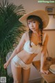 A woman in a white bra and a straw hat posing for a picture.