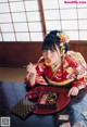 A woman in a kimono sitting at a table eating food.