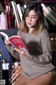 A woman sitting on a chair reading a book.