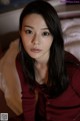 A woman with long black hair sitting on a bed.