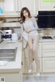 A woman sitting on top of a kitchen counter next to a sink.