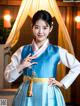 A woman in a blue and white hanbok poses for a picture.