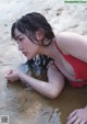 A woman in a red bathing suit laying in the water.