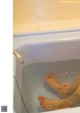 A person's feet in a bathtub with water coming out of it.